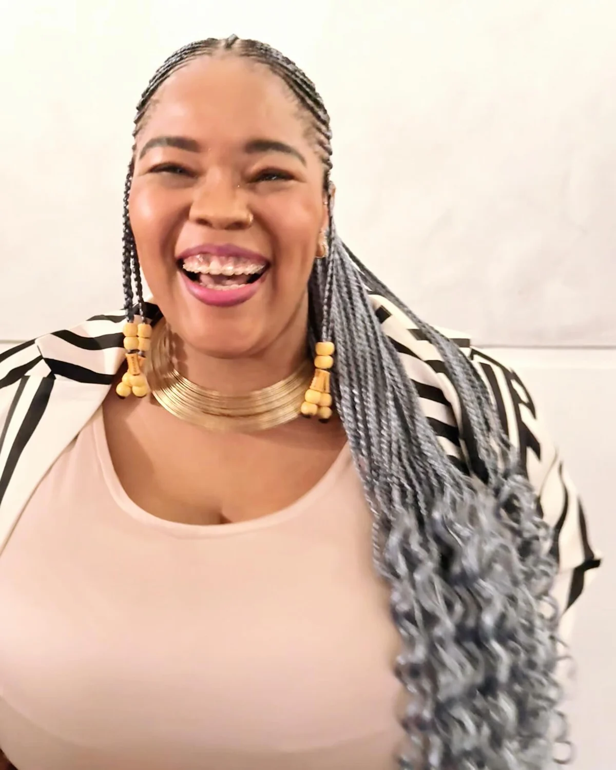 Bonolo laughing, wearing silver braids and a striped jacket