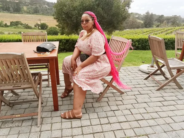 Bonolo with pink braids seated outside overlooking vineyards in Cape Town